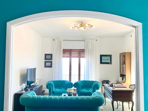 - un salon avec un canapé bleu et des chaises dans l'établissement 2 bedrooms apartement with sea view and enclosed garden at Taormina 2 km away from the beach, à Taormine