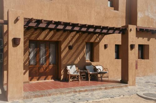 a patio with two chairs and a table on the side of a building at Tzila Bahariya in Az Zaytūn