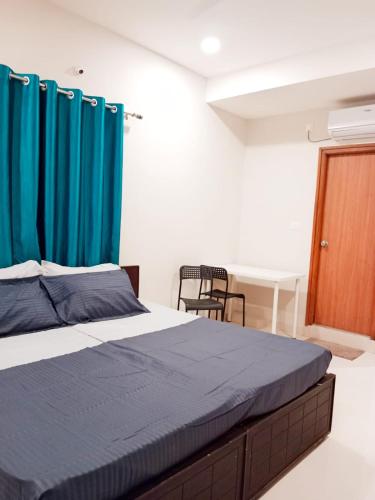a bedroom with a bed with blue curtains and a desk at Nectar Living - Iris in Hyderabad