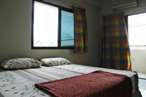 a bed in a bedroom with two windows at Saeng Chan Apartment in Hat Yai