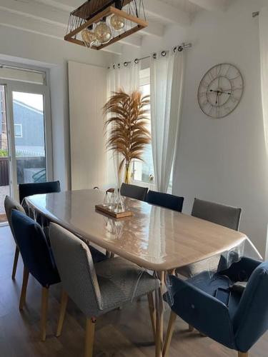 une table à manger avec des chaises et une horloge murale dans l'établissement Villa Sainte-Anne - Ploemeur, à Ploemeur