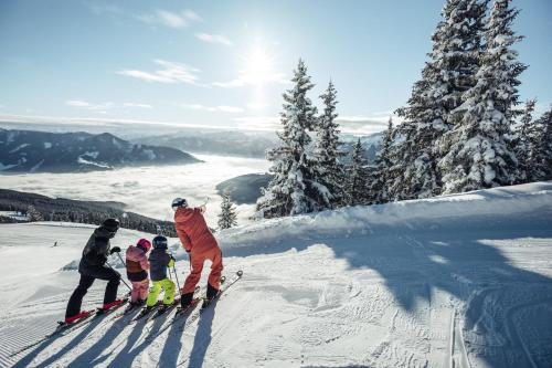 a group of people on skis on a snow covered slope at AlpenParks Hotel & Apartment Central Zell am See in Zell am See