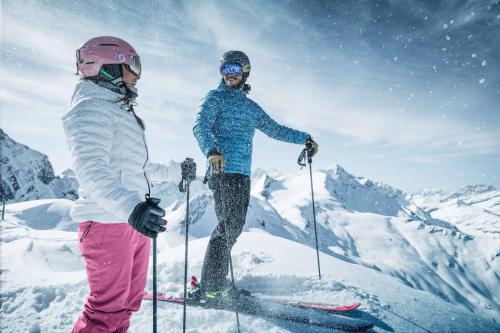 two people on skis in the snow on a mountain at AlpenParks Hotel & Apartment Central Zell am See in Zell am See