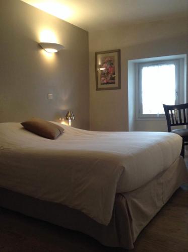 a large white bed in a bedroom with a window at Hôtel Restaurant de la Place in Saint-Jean-dʼAngély