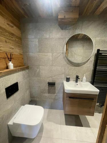 une salle de bain avec un lavabo, des toilettes et un miroir dans l'établissement Le Petit Cham - Cosy and Stylist with Balcony View, à Morzine
