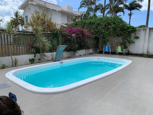 una piscina en un patio con sillas alrededor en Vila dos Lençóis en Santa Cruz Cabrália