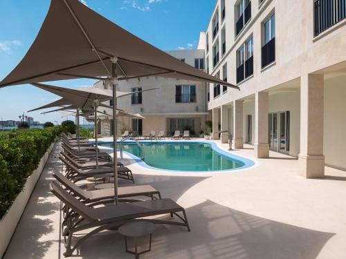una fila di sedie a sdraio con ombrelloni e piscina di Dolce Vista Suite Apartment Garden Palace Resort a Umag (Umago)