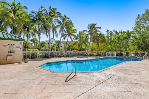 a swimming pool with a fence and palm trees at Sunrise Suites - Saint Kitts 412 in Key West