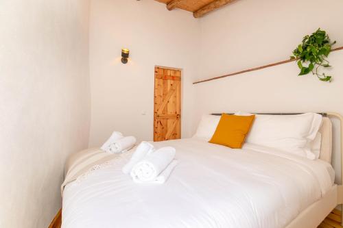 a bedroom with a white bed with orange and white pillows at Casa Soneca in Sagres