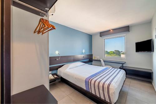 um quarto de hotel com uma cama e uma televisão em City Express Junior by Marriott Ciudad del Carmen em Ciudad del Carmen