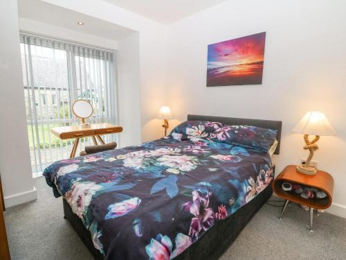 Un dormitorio con una cama y un escritorio y una ventana. en Cysgod Y Capel, en Benllech