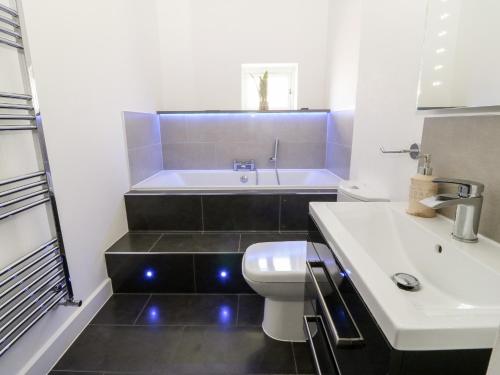 Un baño con bañera, inodoro y lavabo. en Cysgod Y Capel, en Benllech