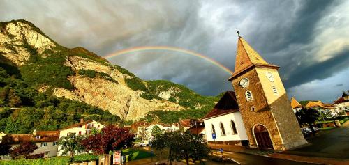 a rainbow over a church with a clock tower at Appartement Les Salines in Roche