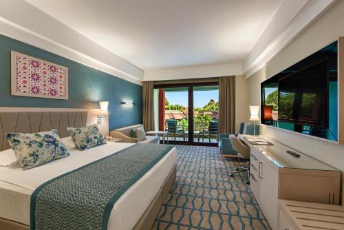 a hotel room with a bed and a flat screen tv at Megasaray Club Belek in Belek