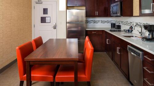 a kitchen with a wooden table and orange chairs at Residence Inn by Marriott Jacksonville South Bartram Park in Jacksonville