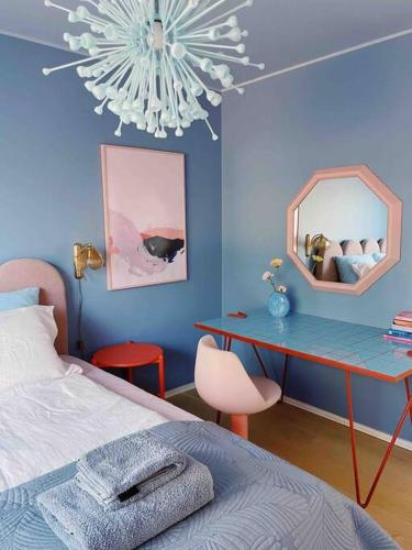 1 dormitorio con pared azul, mesa y espejo en Ihana kaksio Linnanmäen vieressä, en Helsinki