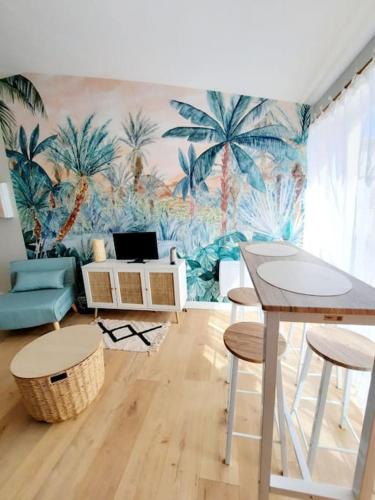 d'un salon orné d'une fresque murale représentant des palmiers. dans l'établissement Studio piscine proche plage et village naturiste, au Cap d'Agde