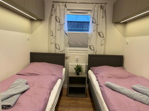 2 Betten in einem kleinen Zimmer mit Fenster in der Unterkunft Haus MeerAuszeit - Erholung an der Nordsee in Schweiburg