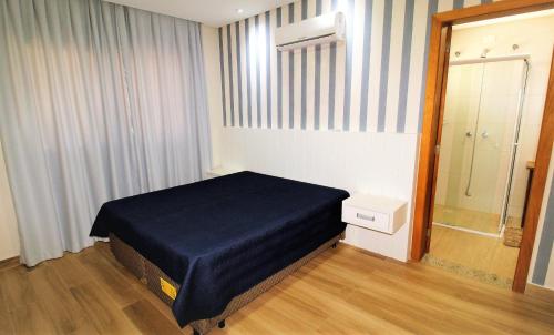 1 dormitorio con cama, ventana y espejo en 1079 - Apartamento com vista para o mar em Bombinhas, en Bombinhas