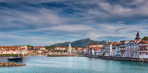 a town with a river and a boat in the water at Boutique H&ocirc;tel Txoko in Saint-Jean-de-Luz