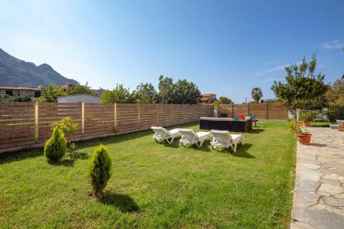 a yard with a row of white chairs and a fence at Villa Marietta in Agios Gordios
