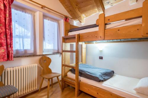 a bedroom with two bunk beds and a chair at Villetta Clara in Vigo di Fassa