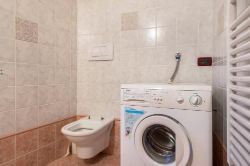 a bathroom with a washing machine and a toilet at Villetta Clara in Vigo di Fassa