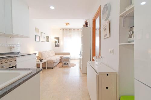 プエルト・デ・サグントにあるGlobal Properties, Practico apartamento en Puerto de Sagunto cerca de la playaのキッチン、リビングルーム(白いキャビネット、ソファ付)