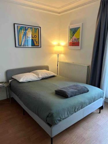 a bed in a bedroom with a lamp and paintings on the wall at Appartement Quartier Tour Eiffel in Paris