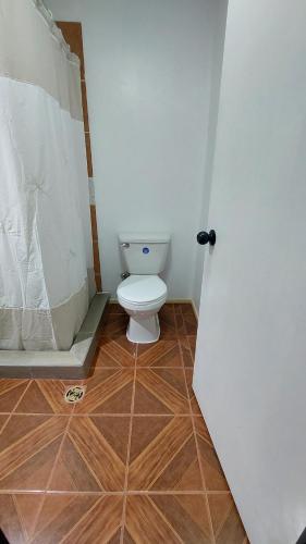 a bathroom with a toilet and a wooden floor at Pieza independiente 2 camas in Los Ángeles