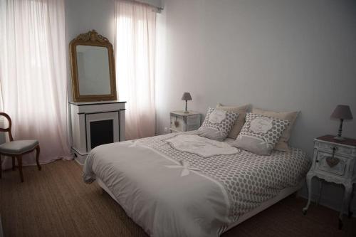 Schlafzimmer mit einem Bett mit einem Spiegel und einem Kamin in der Unterkunft Bel appartement en pierre de 100 m2 avec cour. in Margaux
