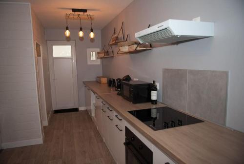 eine Küche mit einer Arbeitsplatte und einer Mikrowelle in der Unterkunft Bel appartement en pierre de 100 m2 avec cour. in Margaux