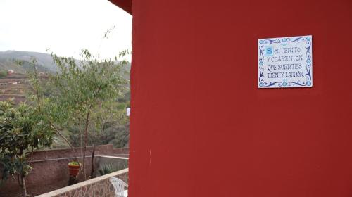 a sign on the side of a red wall at Casa rural Finca Don Amado, San Mateo in Las Palmas de Gran Canaria