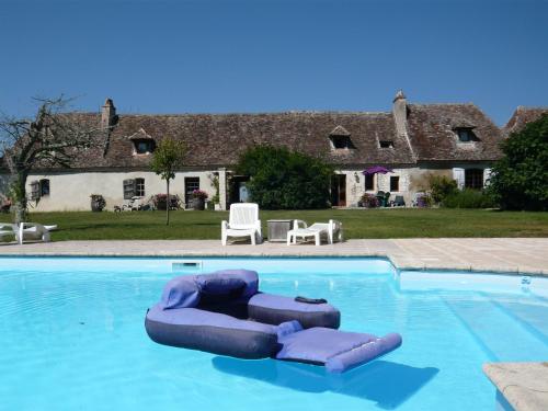 une piscine avec un radeau gonflable violet en face d'une maison dans l'établissement Domaine de Fumel Le Sauvignon, à Issigeac