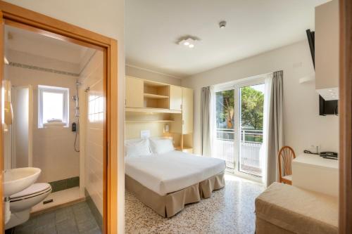 a bedroom with a bed and a bathroom with a sink at Hotel Atenea Golden Star in Caorle