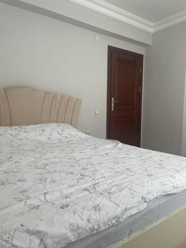 a white bed in a white room with a brown door at Deniz ve Giresun manzaralı daire in Boztekke