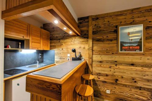 a kitchen with wooden walls and a counter with a stove at Superbe appartement au pied des pistes -Le chamois in Les Déserts