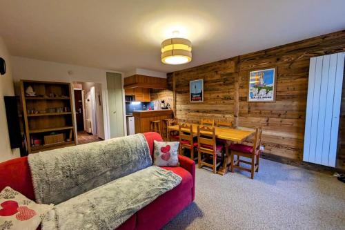 a living room with a red couch and a table at Superbe appartement au pied des pistes -Le chamois in Les Déserts