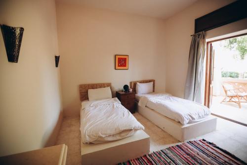 two beds in a room with a window at Tzila Bahariya in Az Zaytūn