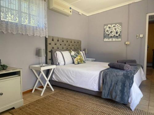 a bedroom with a large bed with a table and a bed sidx sidx at Shades of grey in Oudtshoorn