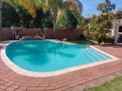 a large swimming pool in a yard with a brick wall at Shades of grey in Oudtshoorn