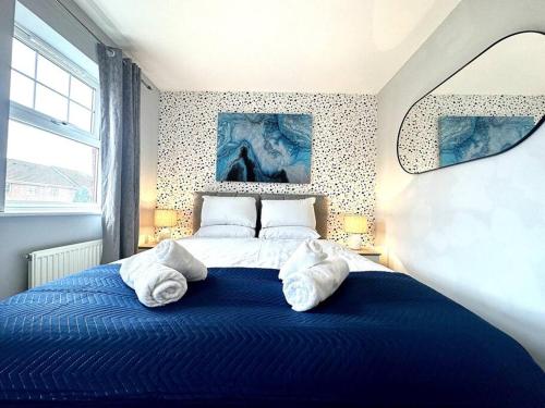 a bedroom with a blue bed with towels on it at Newham House by Blue Skies Stays in Stockton-on-Tees
