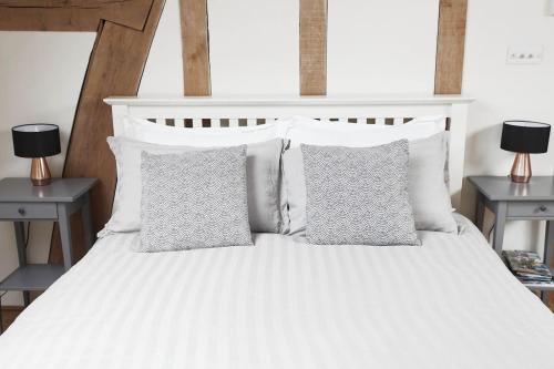 ein weißes Bett mit vier Kissen und zwei Lampen in der Unterkunft Acorn Barn in Crediton