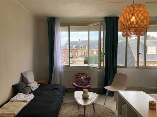 a bedroom with a bed and a table and a window at Grand studio avec petite vue mer in Mers-les-Bains