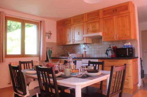 une cuisine avec une table et des chaises blanches, une table et des armoires dans l'établissement Whole cosy and comfy apartment, Valmeinier 1500, with terrace, à Valmeinier