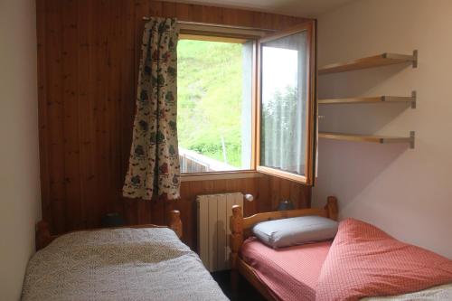 Cette chambre comprend deux lits et une fenêtre. dans l'établissement Whole cosy and comfy apartment, Valmeinier 1500, with terrace, à Valmeinier