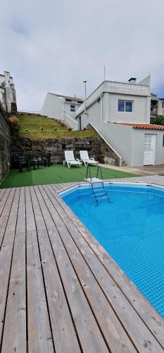 a swimming pool with a wooden deck next to a house at Casa Vista do Monte in Povoação