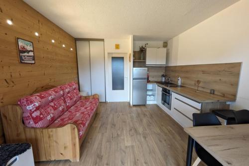 uma sala de estar com um sofá e uma cozinha em Chaleureux studio au pied des pistes - Le refuge em Les Déserts