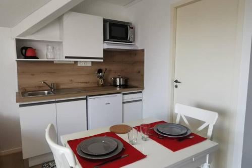 una pequeña cocina con mesa y microondas en Studio 2 pers avec accès piscine et sauna en Les Déserts