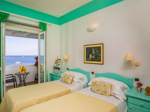 twee bedden in een kamer met uitzicht op de oceaan bij Hotel Ossidiana Stromboli Center in Stromboli